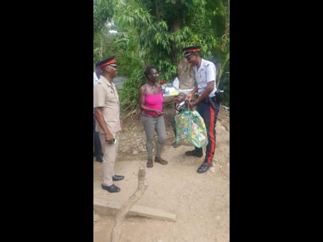 Members of the Annotto Bay Police Station in St Mary hand over some groceries to Karen Samuels, who was in need of help.