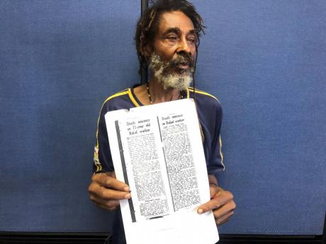 Credit: Romardo Lyons Lynden Minott with an article written about his father’s death penalty.