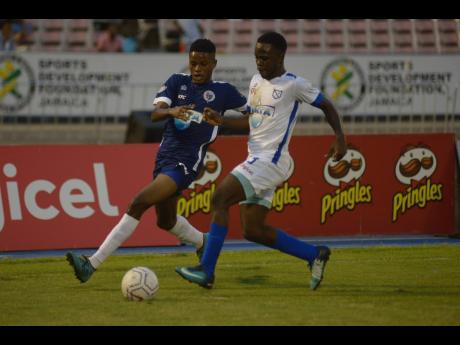 Jamaica College’s (JC)  Jonoi Williams (left) challenges McGrath’s Nathaniel McKenzie during the ISSA Champions Cup match at the National Stadium on November 2, 2019.
