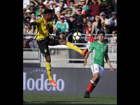 Jamaica’s Alvas Powell (left) controls the ball against Mexico’s Erick Gutierrez (right) during the first half of a Concacaf Gold Cup semi-final match on July 23, 2017.