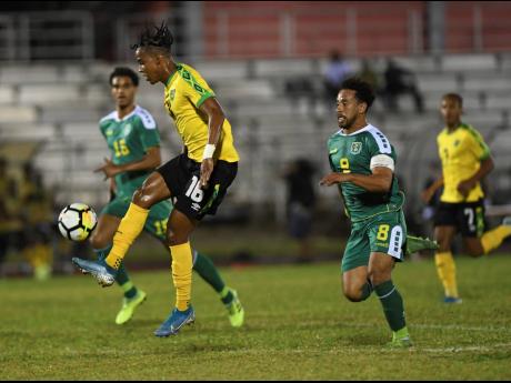 Jamaica’s Peter-Lee Vassell (left) attempts to control the ball while being pursued by Guyana’s Samuel Cox in their League B Group C Concacaf Nations League encounter at the Montego Bay Sports Complex on Monday night.