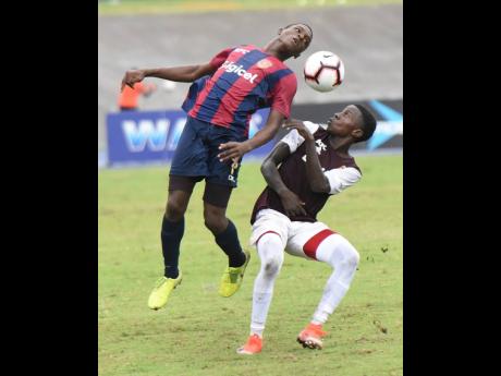 St Andrew Technical High School’s Romario Campbell (left) tries to win a header ahead of Wolmer’s Boys School’s Ty McKetty during their ISSA/Digicel Manning Cup semi-final match at the National Stadium in St Andrew, yesterday.