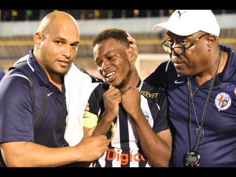 Jamaica College’s Omar Thompson (centre) is overcome with emotion after the win against their rivals Kingston College, and is consoled by team manager Ian Forbes (right) and his assistant Darren Virtue.