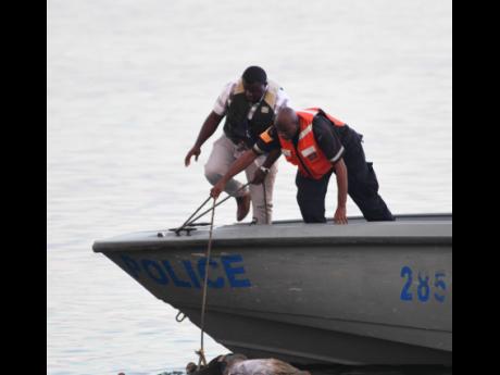 Marine police retrieve the unidentified body from the Kingston Harbour in the vicinity of Flag Circle, off Port Royal Street. According to the Kingston Central police, they were alerted about the body at 3:45 yesterday afternoon. 