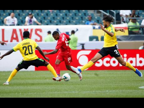 Panama’s Alberto Quintero (centre) kicks the ball past Jamaica’s Kemar Lawrence (left) and Michael Hector during the first half of a  Concacaf Gold Cup match on June 30, 2019.