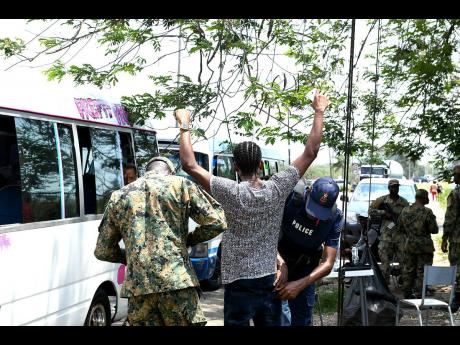 File
Police searching a man at a checkpoint in Spanish Town during a state of emergency in St Catherine.