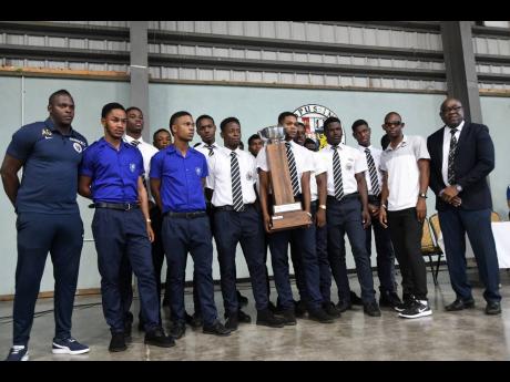 Members of the Jamaica College coaching staff and football team present the Manning Cup trophy to their school community at the Karl Hendrickson Auditorium at Old Hope Road yesterday. 