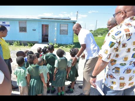 Member of Parliament for Clarendon South East Rudyard Spencer (third right) directs students to view the newly installed solar panels at the St Peter’s Basic School.
