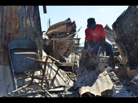 Credit: Kenyon Hemans Glatston March searches through the rubble of what was once his shop. It was destroyed in the massive blaze that occurred on Sunday in a section of the May Pen Market.