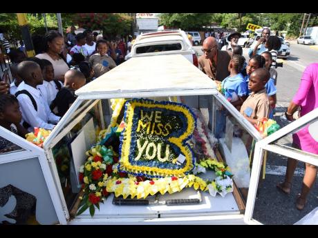 Children gather around the chariot holding Benjamin’s body, as the hearse prepares to head for Dovecot Memorial Park. 