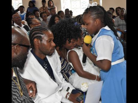 Credit: Ian Allen Courtney Greaves (right), a schoolmate of Benjamin’s, offers a rosebud to members of his family during the funeral.