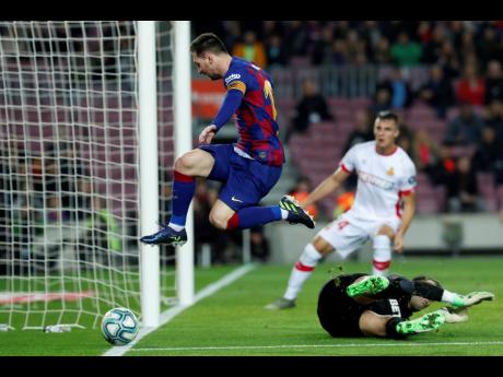 Barcelona’s Lionel Messi leaps over Mallorca’s goalkeeper Manolo Reina, on the ground, during a Spanish La Liga match between Barcelona and Mallorca at Camp Nou stadium in Barcelona, Spain, last Saturday.
