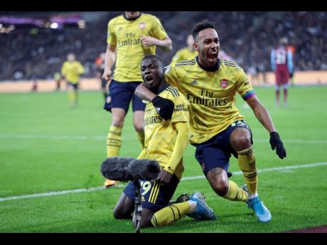 Arsenal’s Nicolas Pepe, left, celebrates with Arsenal’s Pierre-Emerick Aubameyang after scoring his side’s second goal during the English Premier League match between West Ham Utd and Arsenal at the London Stadium in London, yesterday.