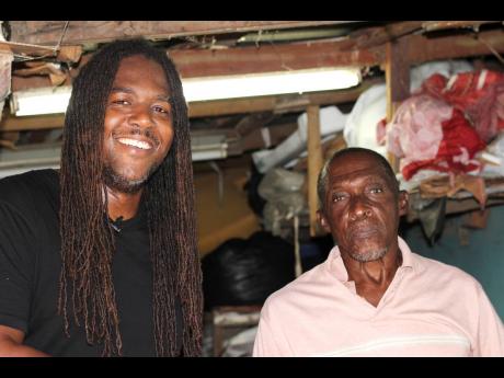 Bay-C shares a moment with Swallowfield resident Mr Campbell, inside his upholstery workshop in Swallowfield, St Andrew.