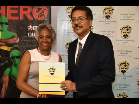 Professor Stephen Vasciannie, president of the University of Technology, hands over the module for the web-based platform to Sandra Glasgow, chairperson of the National Crime Prevention Fund at Crime Stop.