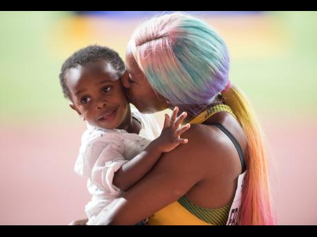 Shelly-Ann Fraser-Pryce celebrates winning her fourth World 100m title by kissing her son, Zyon, on September 29.