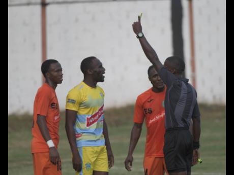 Tivoli Gardens players Rochane Smith (left) and Kemar Flemmings (second right) look on as Waterhouse’s Kymani Campbell (second left) is cautioned  by referee Christopher Mason (right) during their Red Stripe Premier League match at the Edward Seaga Sports Complex yesterday.