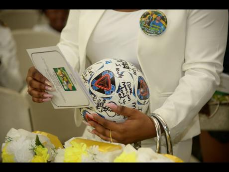 Kadian Clarke, sister of Tarania, lays a ball signed by family, friends, and former teammates in her casket during the funeral service to remember her life at the Excelsior High School Auditorium yesterday.