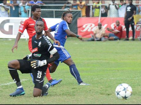 Mount Pleasant's Kemar Beckford (right), flicks the ball beyond advancing UWI goalkeeper Amal Knight (front) to score in their Red Stripe Premier League game at Drax Hall in St Ann on Sunday, March 31, 2019.