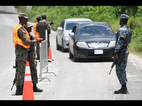 A Jamaica Defence Force personnel mans a checkpoint in Whitehouse, Westmoreland last year after the state of public emergency was declared for the parish.