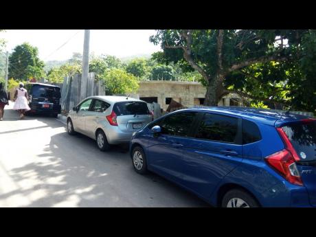 Photo shows a number of vehicles parked outside the home of Rajui Brown, the man who allegedly shot himself to death at Binns Lane in Elgin Town, Hanover, last Saturday.