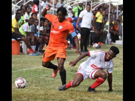 Tivoli Gardens captain Kemar Flemmings (left) evades a tackle from UWI’s Nacquain Brown during their Red Stripe Premier League match at the Edward Seaga Complex yesterday.