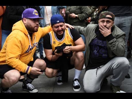 Los Angeles Lakers fans Alex Fultz, from left, Eddy Rivas and Rene Alfaro react to the death of former NBA player Kobe Bryant outside of the Staples Center prior to the 62nd annual Grammy Awards yesterday.