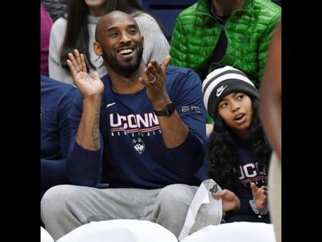 In this March 2, 2019 photo, Kobe Bryant and his daughter Gianna watch the first half of an NCAA college basketball game between Connecticut and Houston in Storrs, Connecticut.