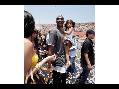 In this June 17, 2009 file photo Los Angeles Lakers’ Kobe Bryant smiles as he and his daughter Gianna Maria-Onore walk up the steps after the victory parade celebrating the Lakers’ NBA championship in Los Angeles. 