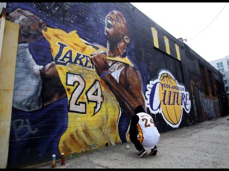 A fan pays respects at a mural depicting Kobe Bryant in a downtown Los Angeles alley after word of the Lakers star’s death in a helicopter crash, in downtown Los Angeles yesterday.