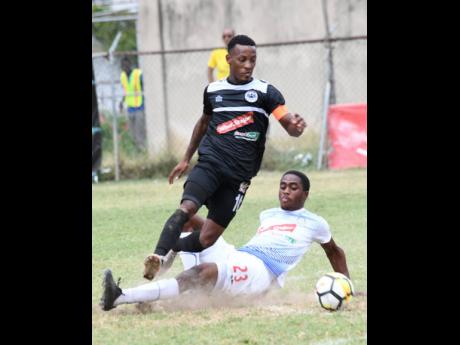 Emelio Rousseau (right) of Portmore United puts in a sliding challenge on Chevone Marsh of Cavalier during a Red Stripe Premier League match on Sunday, February 10, 2019.