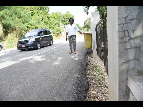 Some residents have difficulty accessing their homes following the acquisition of their lands to accommodate the road expansion. Buelah Morgan, for example, steps out of her yard and on to the roadway.