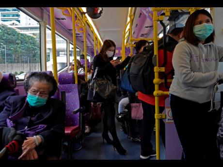 People wear protective face masks on a bus in Hong Kong on Tuesday. Hong Kong reported its first death from coronavirus, a man who had travelled from the mainland city of Wuhan that has been the epicentre of the outbreak.