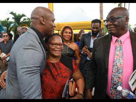 Asafa Powell shares a hug with his mother, Cislyn as his father William looks on before the unveiling of a statue of the former world record holder yesterday at Independence Park. 
