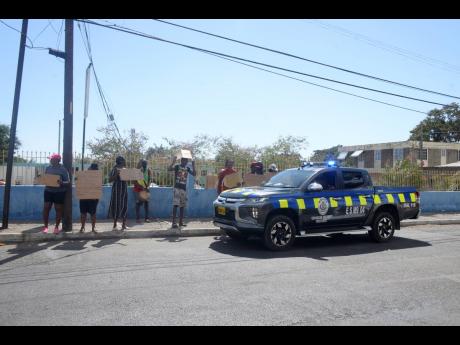 Police personnel keep a close eye on protesters who are against the government’s decision to make the 
St Joseph’s Hospital a quarantine centre. 