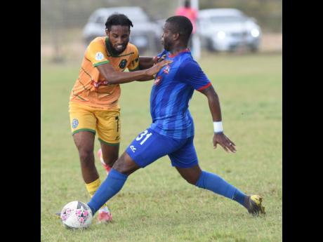 Vere United’s Christopher Randall (left) runs into a tackle from Rodave Murray (right) of Dunbeholden FC in their Red Stripe Premier League football match yesterday.