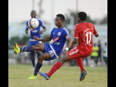 Mount Pleasant’s Kemar Beckford (left) brings the ball under control while being watched by UWI defender Stephen Barnett during a Red Stripe Premier League match last season. Beckford is the leading scorer in this year’s competition. 