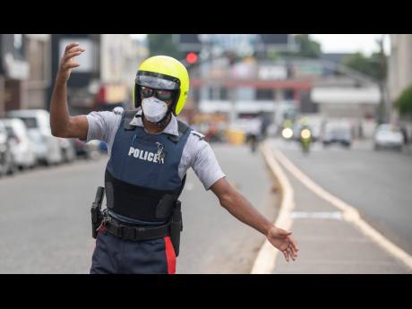 Credit: Gladstone Taylor A member of the Jamaica Constabulary Force directs traffic in New Kingston while wearing a mask as a preventative measure against COVID-19.
