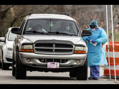 A man and woman get tested for COVID-19 at a drive-through testing site at Cone Health Ambulatory and Physician Services in North Carolina, yesterday.
