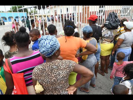 
A crowd at the gate of New Hope Preparatory School on North Street in Kingston on Tuesday to collect food being distributed under the PATH programme.
