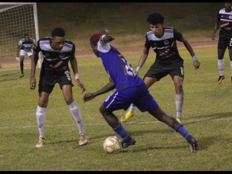 Former Cavalier defender Jamoi Topey (left) watches the ball as Reno’s Famcy-Hue Stewart (centre) drives forward during a Red Stripe Premier League match at Stadium East in 2018.