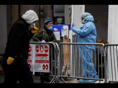 A medical worker speaks with patients at a COVID-19 testing station at the Brooklyn Hospital Center in New York. 