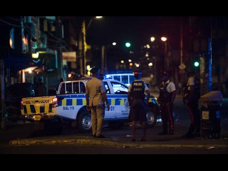 Members of the Jamaica Constabulary Force at West Parade in downtown Kingston, moments before the commencement of the islandwide curfew. 