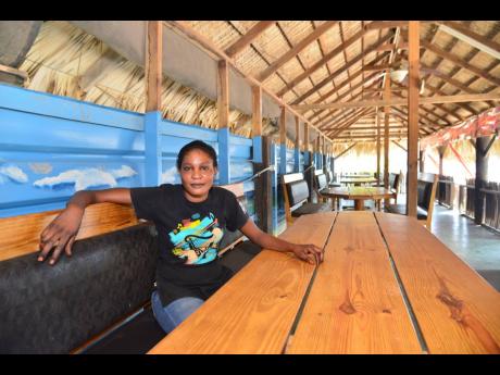 Credit: Kenyon Hemans Jennifer Harvey sits in the empty Rocky Point White Sand Beach Seafood Restaurant in Clarendon on Thursday.