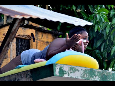 A Denham Town, Kingston, resident takes up position on the top of a roof last Saturday, moments after a 3 p.m. curfew came into effect.