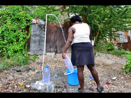 A Denham Town, Kingston, resident catches water at an outdoor pipe. Inner-city residents say the absence of amenities such as piped water is one of the main reasons they cannot stay indoors, despite the imposition of curfews to contain the spread of the novel coronavirus.