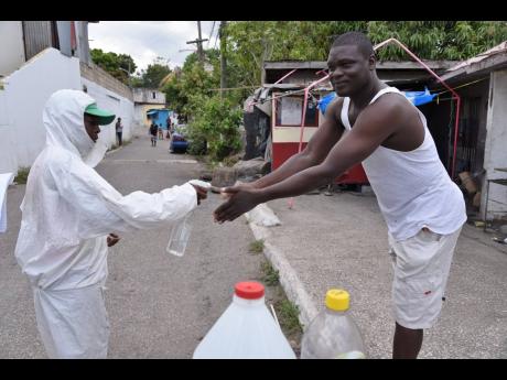 Credit: Ian Allen Baker ensures that both pedestrians and occupants of vehicles are sanitized before entry to Park Lane.