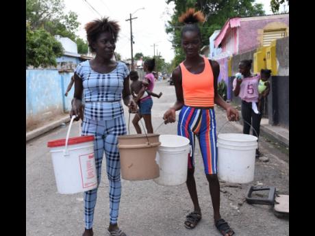 Credit: Ian Allen Ian Allen Photo
Daniesha Taylor (left) and Shamania Brown with buckets ready to catch water from a pipe.