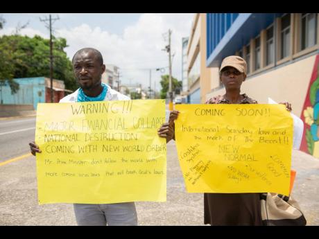 Credit: Gladstone Taylor Jermaine Allen (left) and Jacqueline Murray protest what they believe to be an impending new world order in front of The Gleaner Company Media Limited.