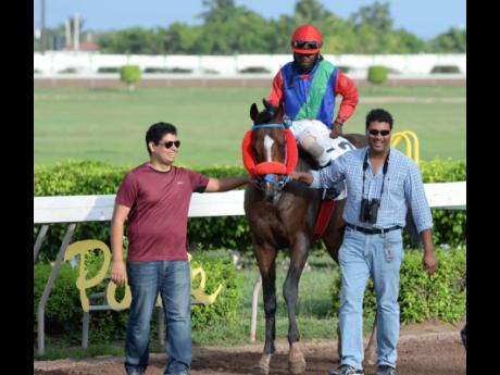 Credit: File Peter-John Parsard (left) and his father, trainer Ian Parsard, guiding SUPERLUMINAL (Robert Halledeen up) to the winners’ enclosure after the horse won an overnight allowance race over 1800 metres at Caymanas Park.